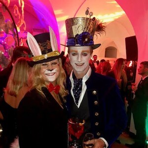 May include: Two people dressed in costumes for a party. One person is wearing a white rabbit costume with a gold and black hat. The other person is wearing a blue and gold top hat with a blue and white patterned shirt and a blue velvet jacket.