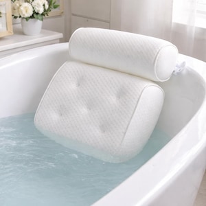 May include: A white, cushioned bath pillow set in a white bathtub filled with water. The set includes a headrest and a backrest, both with a textured surface and button detailing. The pillow is designed for comfort and relaxation during bathing.