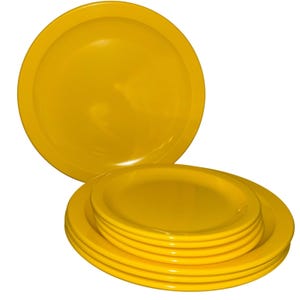 Puede incluir: Un conjunto de platos de color amarillo brillante. Los platos tienen un diseño sencillo y clásico con un borde ligeramente elevado. Están hechos de un material brillante y son de un color amarillo sólido y vibrante. Un plato está en el fondo.