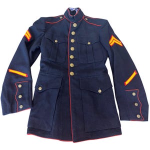 May include: A navy blue military jacket with red trim and gold buttons. The jacket features gold and yellow stripes on the sleeves, and multiple pockets. The jacket is a vintage style.