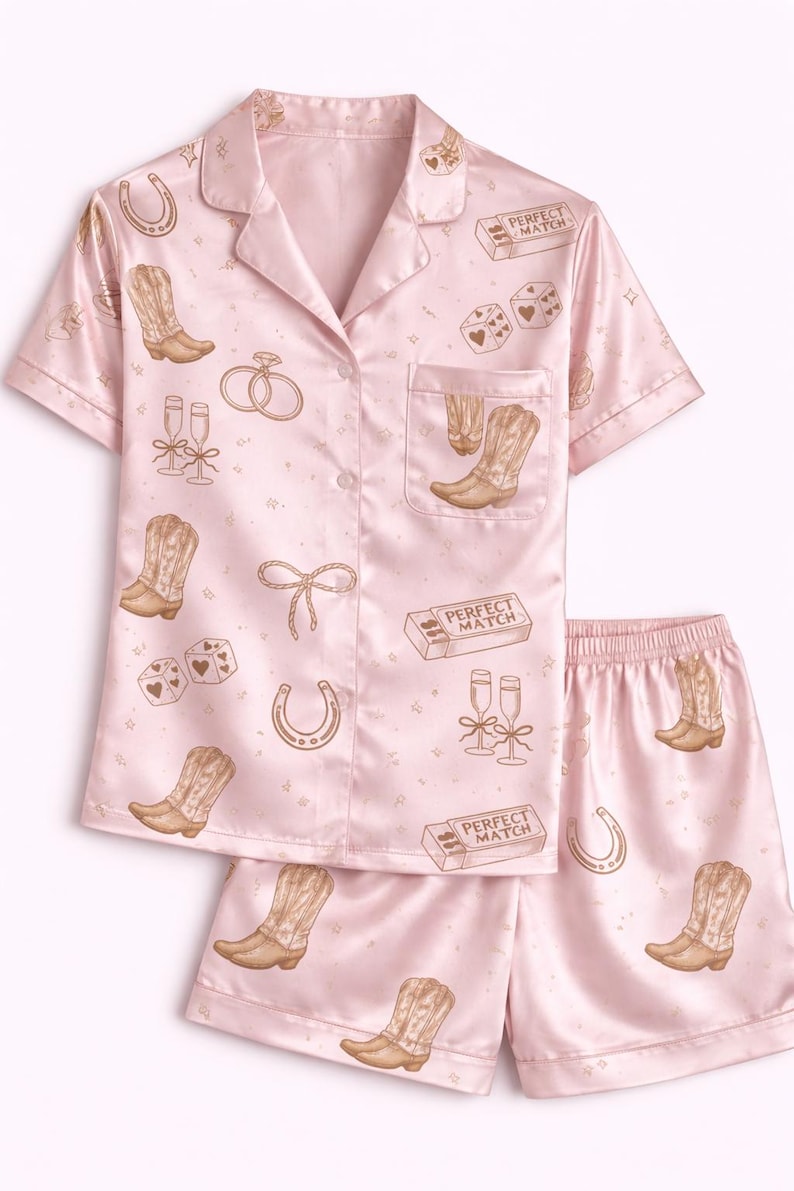 May include: Pale pink pyjama set featuring a button-down shirt and shorts. The set is patterned with cowboy boots, dice, horseshoes, champagne flutes, and the text "PERFECT MATCH".