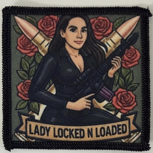 May include: Embroidered patch featuring a woman holding a rifle, with two bullets and red roses in the background. The text "LADY LOCKED N LOADED" is displayed on a banner. The patch has a black border.