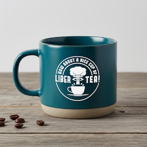 Op de afbeelding: Een witte keramische mok met een zwarte handgreep en de tekst "But First, Coffee" in een vetgedrukte, zwarte letter. De mok staat tegen een vage achtergrond, wat een gezellige setting suggereert.