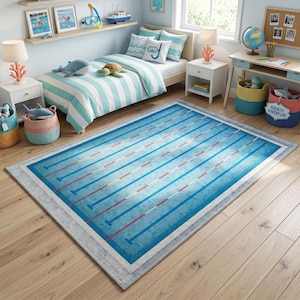 Könnte beinhalten: Ein rechteckiger Teppich mit einem Schwimmbad-Design. Der Teppich hat einen hellblauen Hintergrund mit dunkleren blauen und roten Bahnen. Ein grauer Rand umrahmt das Pool-Design und schafft ein verspieltes Wasser-Thema.