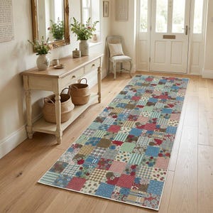 May include: A long rectangular runner rug featuring a patchwork design composed of various square fabric patterns in shades of blue, red, green, and beige, including floral, plaid, striped, and polka dot motifs, laid out on a wooden floor.