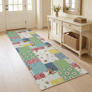 May include: A rectangular runner rug featuring a patchwork design with various patterns including floral prints, polka dots, and gingham checks in shades of green, red, blue, yellow, and white, laid out on a light-colored wooden floor surface.