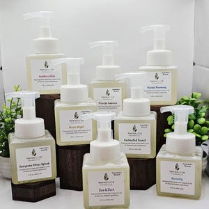 May include: A collection of eight square clear plastic foaming hand soap bottles with white pump dispensers. Each bottle features a white label with the Thymeless Naturals LLC logo, scent name, and the text 8 fl. oz. (236.6 ml).