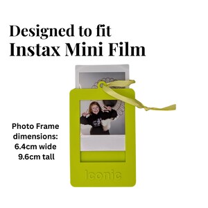 May include: A lime green photo frame designed for Instax Mini Film, with a photo inside. The frame is 6.4cm wide and 9.6cm tall, with a yellow ribbon attached. The word "Iconic" is printed on the bottom.