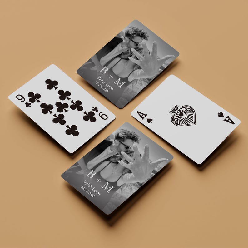 Puede incluir: Se muestran cuatro naipes, incluyendo un nueve de tr&eacute;boles y un as de picas. Dos cartas presentan una foto en blanco y negro con las iniciales "B+M" y la fecha "10.25.2025". Las cartas est&aacute;n sobre una superficie beige.