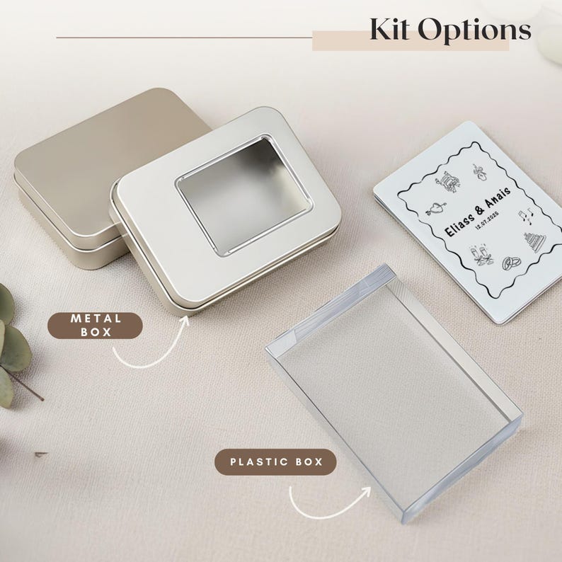May include: Kit options featuring a silver metal box with a clear window, a silver metal box, a clear plastic box, and a white card with black text and illustrations. The text on the card reads "Eliass & Anais" and a date.