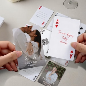 May include: White playing cards with red suit symbols and text. One card features a photo of a couple kissing, with the text "S + A", names, and a date. Another card reads "Forever begins today cheers!" in red script.