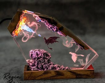 May include: A decorative resin lamp featuring a fantasy scene with dragons and colorful smoke effects. The lamp has a wooden base and frame, with the text "Resin Boys" on the front. The interior scene includes a mountain and two dragons.