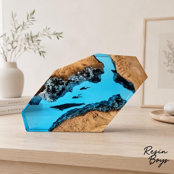 A blue whale and couple of divers suspended in luminous blue resin over a wood base — part sculpture, part nightlight, entirely mesmerizing.
