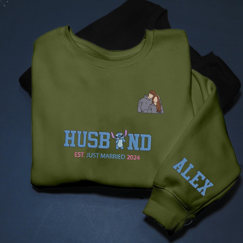 Puede incluir: Sudadera verde oliva con la palabra "HUSBAND" en azul, un personaje de dibujos animados y el texto "EST. JUST MARRIED 2024". Un peque&ntilde;o bordado de una pareja est&aacute; en el pecho. La manga tiene el nombre "ALEX" en azul.