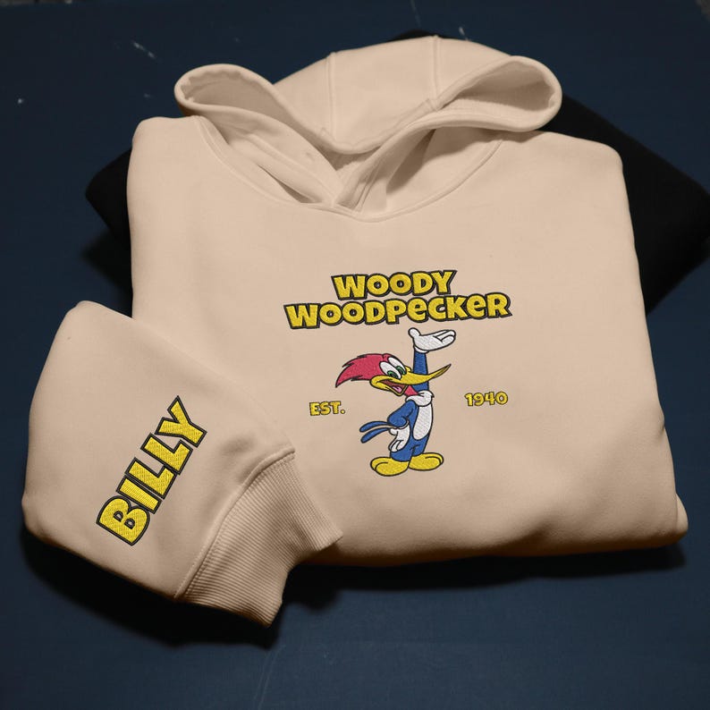 May include: A cream-colored hoodie featuring the cartoon character Woody Woodpecker. The design includes the text "WOODY WOODPECKER" in yellow, the character illustration, and the year "1940". The left sleeve has the name "BILLY" in yellow.