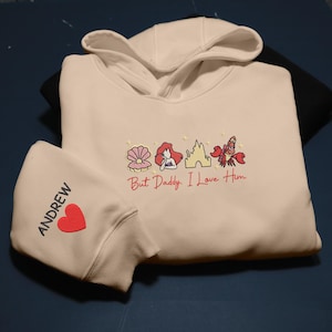 Pode incluir: Uma caneca de cer&acirc;mica branca com uma al&ccedil;a preta e o texto "But First, Coffee" em negrito preto. A caneca est&aacute; sobre uma superf&iacute;cie de madeira. A caneca tem aproximadamente 10 cm de altura.