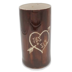 May include: A brown ceramic mug with a heart and arrow design. The heart has the initials "JBS + SLS" inside.