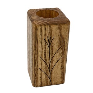 May include: A wooden candle holder with a square base and a carved tree design. The holder is made of natural wood with a brown stain.