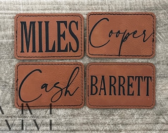 May include: Four rectangular brown leather patches with black stitching. Each patch has a different name in black lettering: MILES, Cooper, Cash, and BARRETT. The Cooper and Cash names are in cursive.