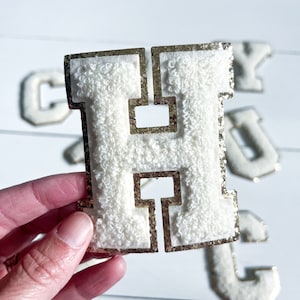 Peut inclure: Une lettre H en feutre blanc avec un contour pailleté doré. La lettre est un élément décoratif et est parfaite pour les projets d'artisanat.