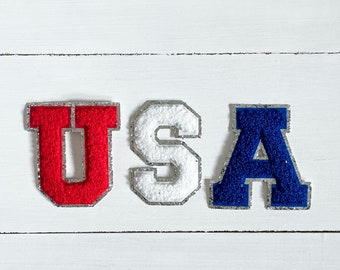 May include: USA spelled out in felt letters. The letters are red, white, and blue.