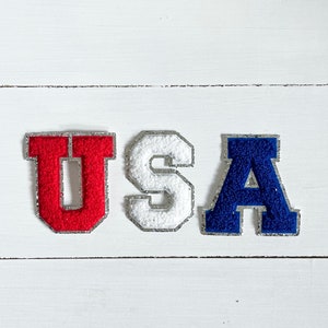 May include: USA spelled out in felt letters. The letters are red, white, and blue.