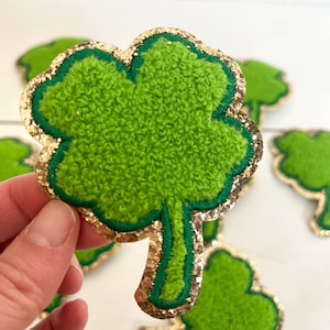 May include: Green felt shamrock with a gold glitter outline. The shamrock is a traditional Irish symbol of good luck.