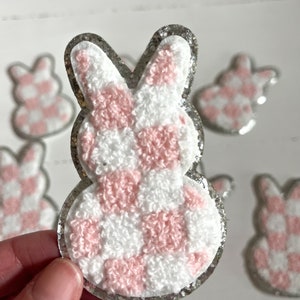 May include: Pink and white checked bunny shaped iron-on patch with a silver glitter border.