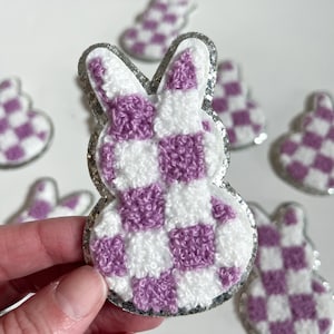 May include: Purple and white checkered bunny shaped iron-on patch with a silver glitter outline.