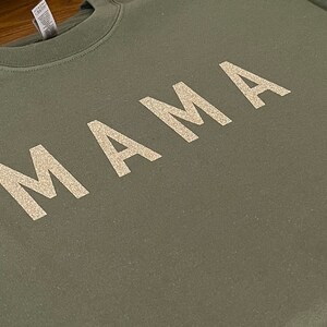 May include: A green sweatshirt with the word "MAMA" written in white glitter.