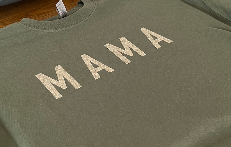 May include: A green sweatshirt with the word "MAMA" written in white glitter.