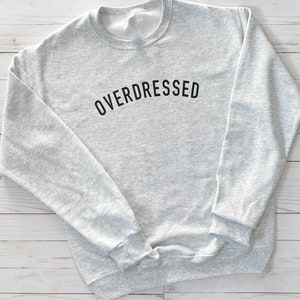 May include: A gray sweatshirt with the text "OVERDRESSED" printed in black on the front.