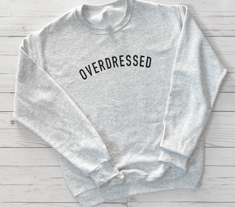 May include: A gray sweatshirt with the text "OVERDRESSED" printed in black on the front.
