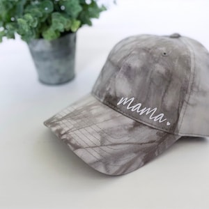 May include: A gray tie-dye baseball cap with the word "mama" embroidered in white on the front.