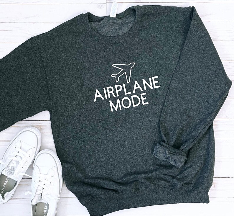 Puede incluir: Una sudadera gris oscuro con el texto "MODO AVI&Oacute;N" en letras blancas y un icono de avi&oacute;n blanco sobre el texto.