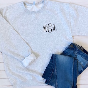 May include: A gray sweatshirt with a black embroidered monogram "MGA" on the front.