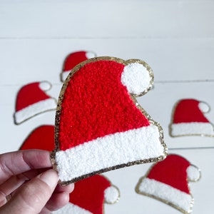 May include: A set of six red and white felt Santa hats with gold glitter trim. The hats are approximately 3 inches tall and 2 inches wide.