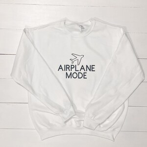 Puede incluir: Sudadera blanca con un gr&aacute;fico de avi&oacute;n negro y el texto "AIRPLANE MODE" impreso en la parte delantera.
