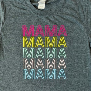 May include: A gray t-shirt with the word "MAMA" repeated five times in a rainbow of colors. Each word is outlined in black.