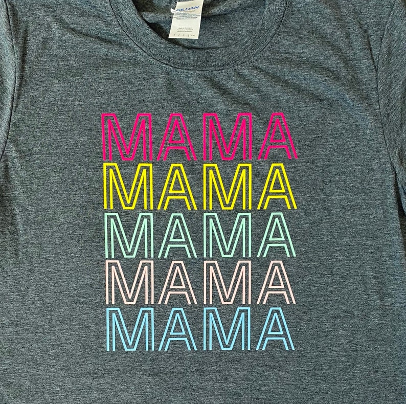 May include: A gray t-shirt with the word "MAMA" repeated five times in a rainbow of colors. Each word is outlined in black.