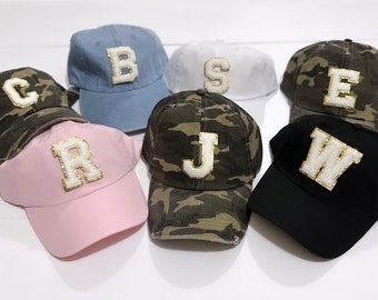 May include: Eight baseball caps with different colored fabrics and letters. The letters are white with gold trim. The letters are C, R, J, B, S, E, and W.
