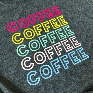 May include: A gray t-shirt with the word "COFFEE" repeated six times in a rainbow of colors, starting with pink and ending with light blue.