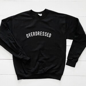 May include: Black sweatshirt with the text "OVERDRESSED" in white lettering.