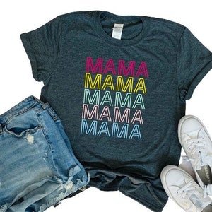 May include: A dark gray t-shirt with the word "MAMA" repeated five times in a rainbow of colors. The text is in a retro, outlined font.