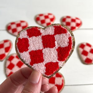 May include: A set of six red and pink checkered heart-shaped patches with gold glitter trim.
