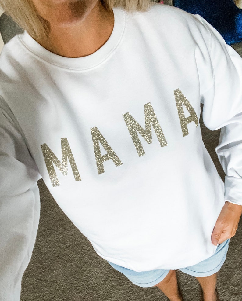May include: White sweatshirt with the word "MAMA" in sparkly silver letters.