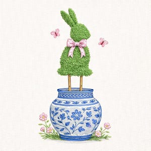 Puede incluir: Un conejito topiario verde con un lazo rosa se encuentra sobre un jarrón floral azul y blanco. Mariposas y flores rosas acentúan el diseño, creando un encantador tema primaveral o de Pascua.