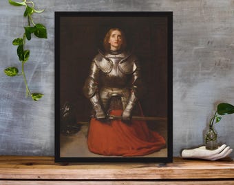 May include: Framed print of a painting depicting a person in full silver armor kneeling on a red garment. The person has long red hair and is looking upwards. The background is a dark, muted color.