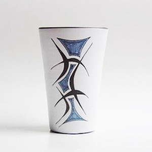 Könnte beinhalten: Eine weiße Keramiktasse mit einem geometrischen Muster in Schwarz und Blau. Das Muster zeigt eine Reihe von abstrakten Formen und Linien.