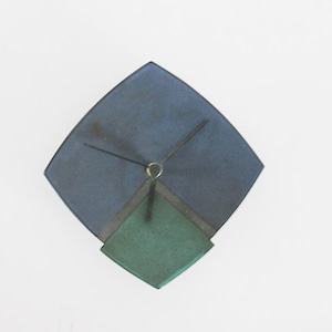 Puede incluir: Un reloj de cerámica azul y verde con agujas negras. El reloj tiene forma de diamante.